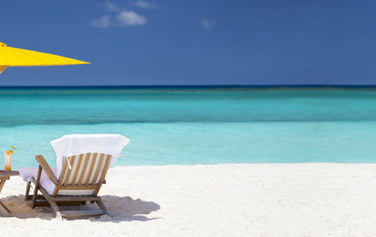 panorama of teak steamers under umbrella at a tropical beach