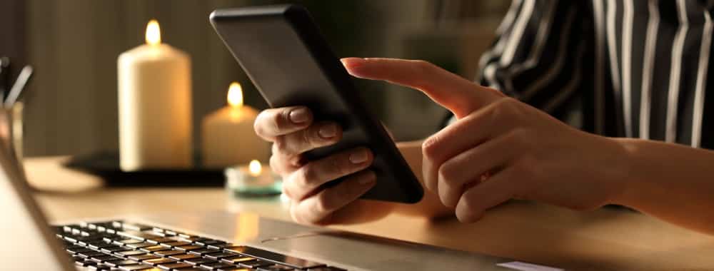 girl-hands-using-phone-on-power-outage-with-candles